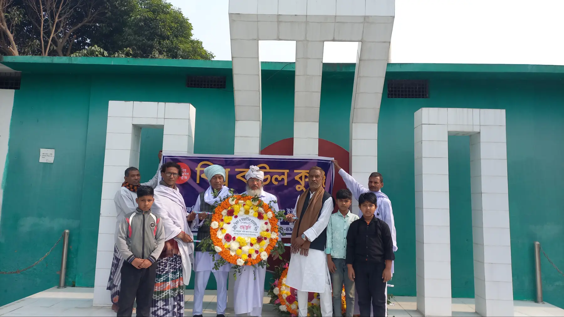 বিশ্ব বাউল কুঞ্জ এর ব্যানার চাঁপাইনবাবগঞ্জ মহিপুর কলেজ শহীদ মিনারে ফুলের শ্রদ্ধা